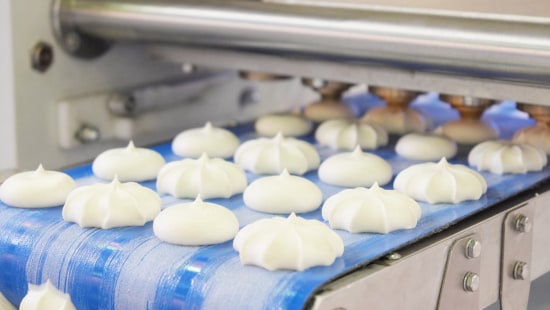 Industrial bakery items being processed on conveyor belt.